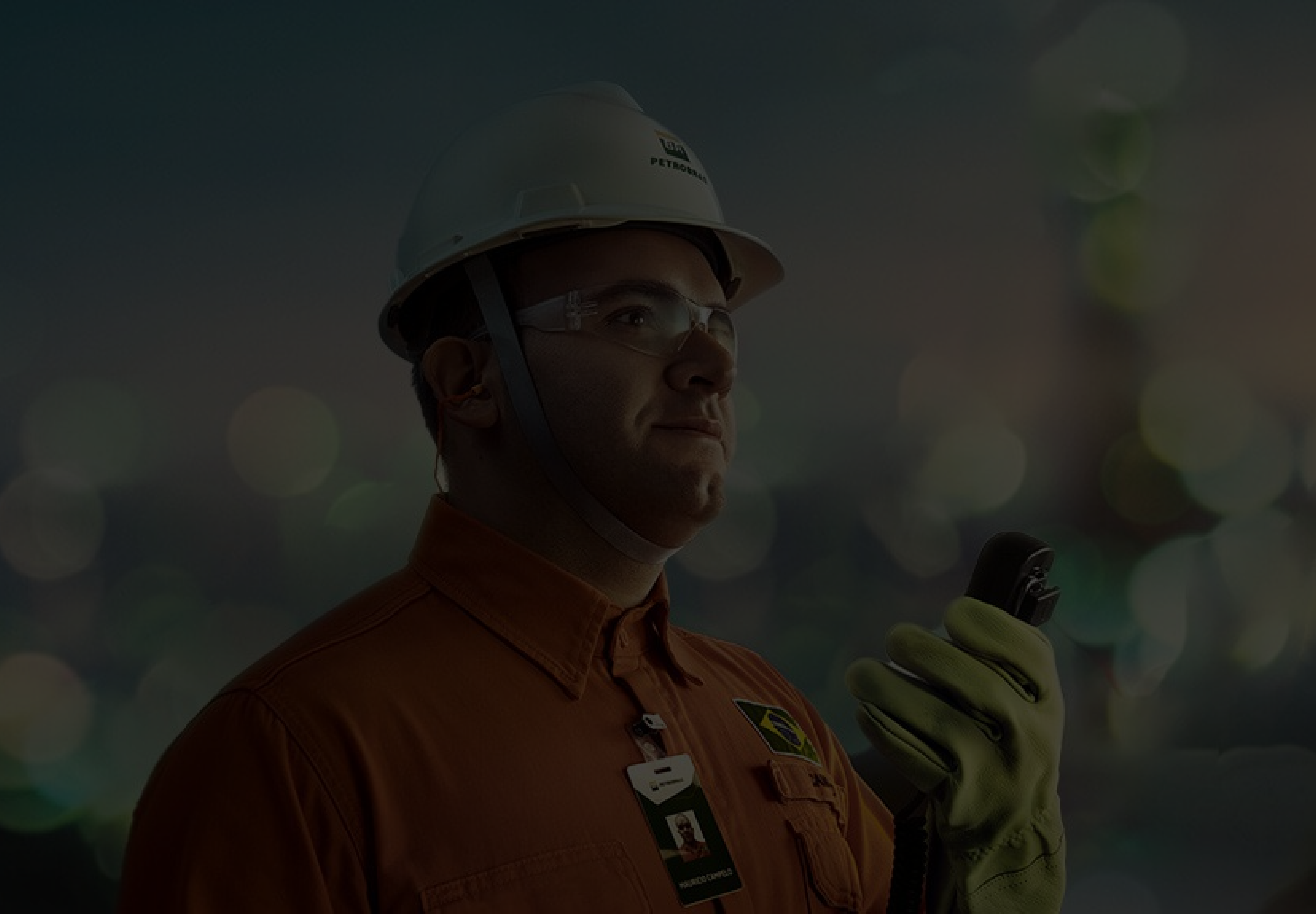 A man in a Petrobras uniform holding a walkie-talkie in his left hand.