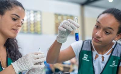 Two young scientists working with a test tube. Inside, there's a blue liquid.