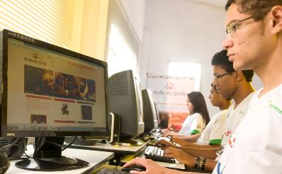 Four young people sitting in front of computers in a computer room.
