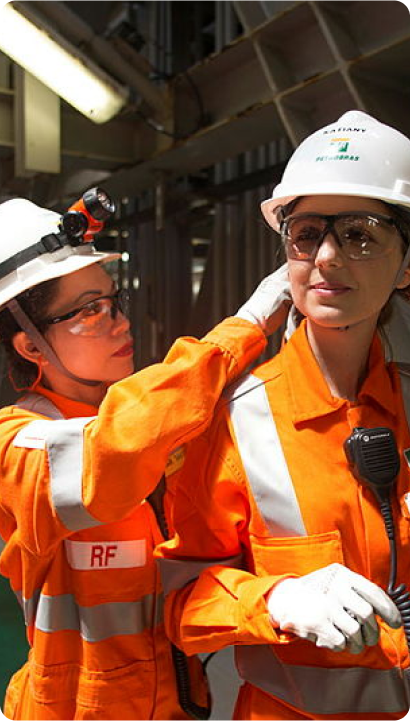 Two Petrobras employees adjusting their equipments to work on a platform.