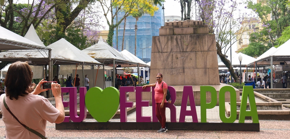 Woman taking a photo next to a sign, "I love POA Book Fair.