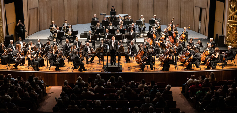 Palco de um concerto da Orquesta Sinfônica, com artistas se apresentando