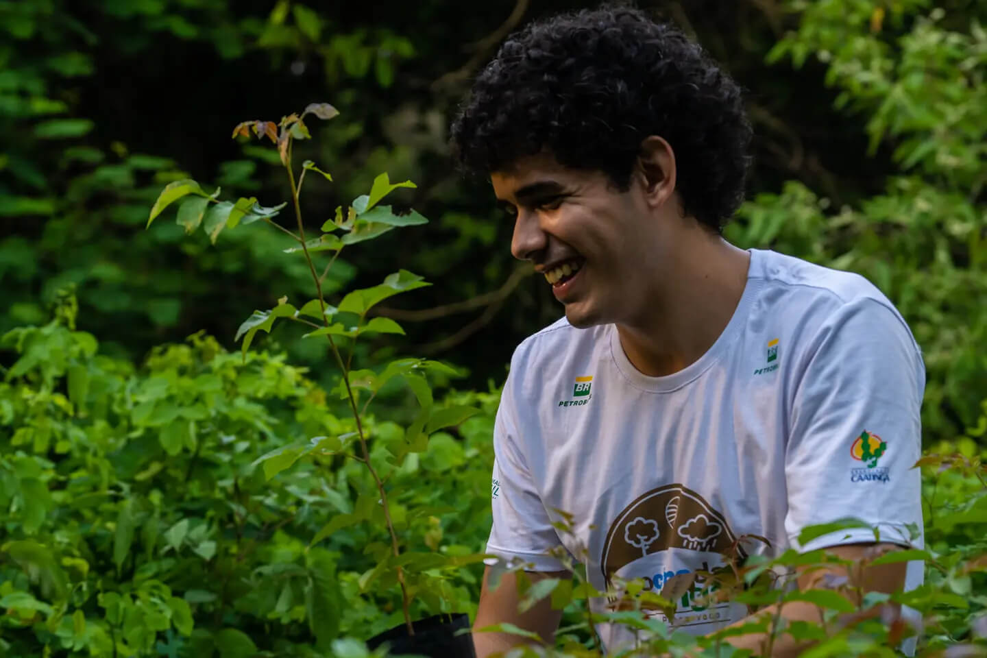 Jovem sorrindo com floresta ao fundo