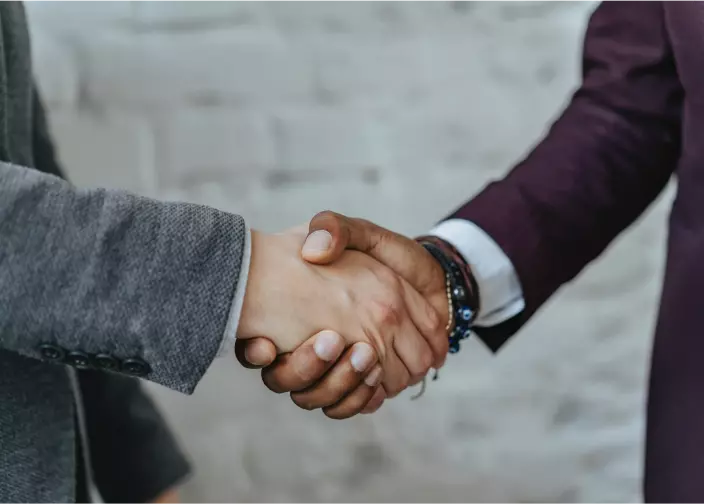 Fotos de um cumprimento de mãos entre duas pessoas usando ternos, representando negócios da Petrobras.