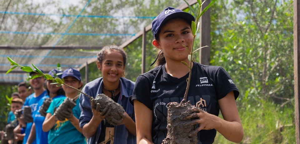 Five young people lined up, holding plants.