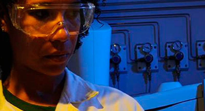 Funcionária da Petrobras com jaleco e epi de laboratório.