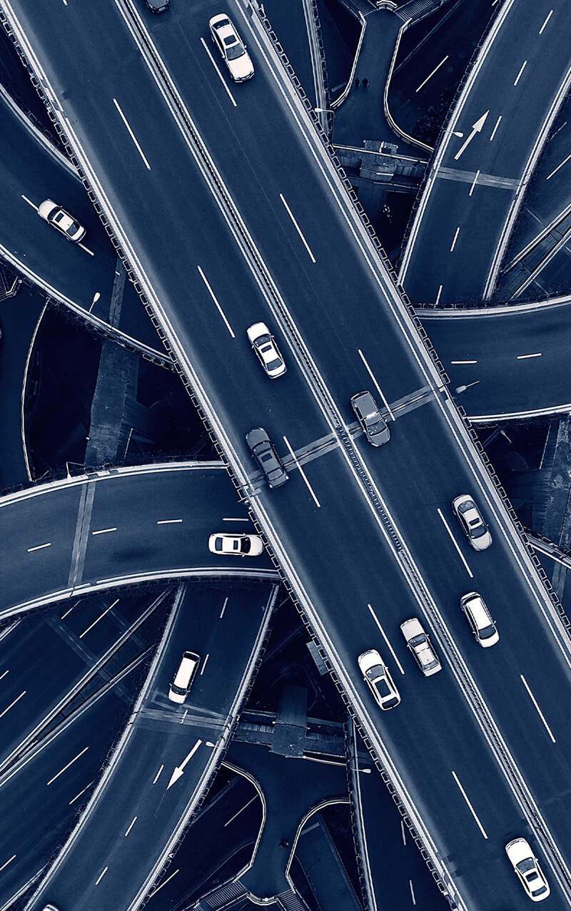 Vista aérea de um entroncamento de rodovias, com alguns carros circulando.